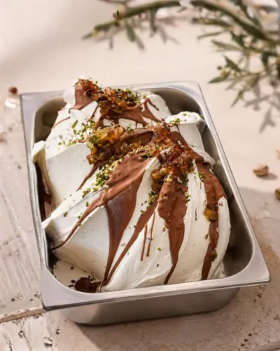 Pistachio gelato with chocolate drizzle in a stainless steel gelato pan