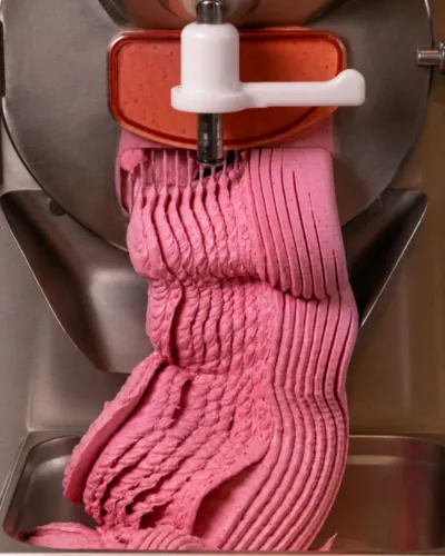 Freshly churned raspberry gelato coming out of a batch freezer